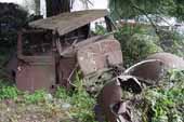 Rough pickup truck cab and fenders stored in vintage car salvage yard