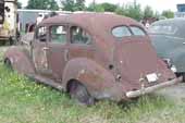 Straight 1940's 4-door sedan in vintage car wrecking yard and ready for restoration