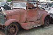 Restorable original 1929 Ford Model A roadster parked at vintage car junkyard